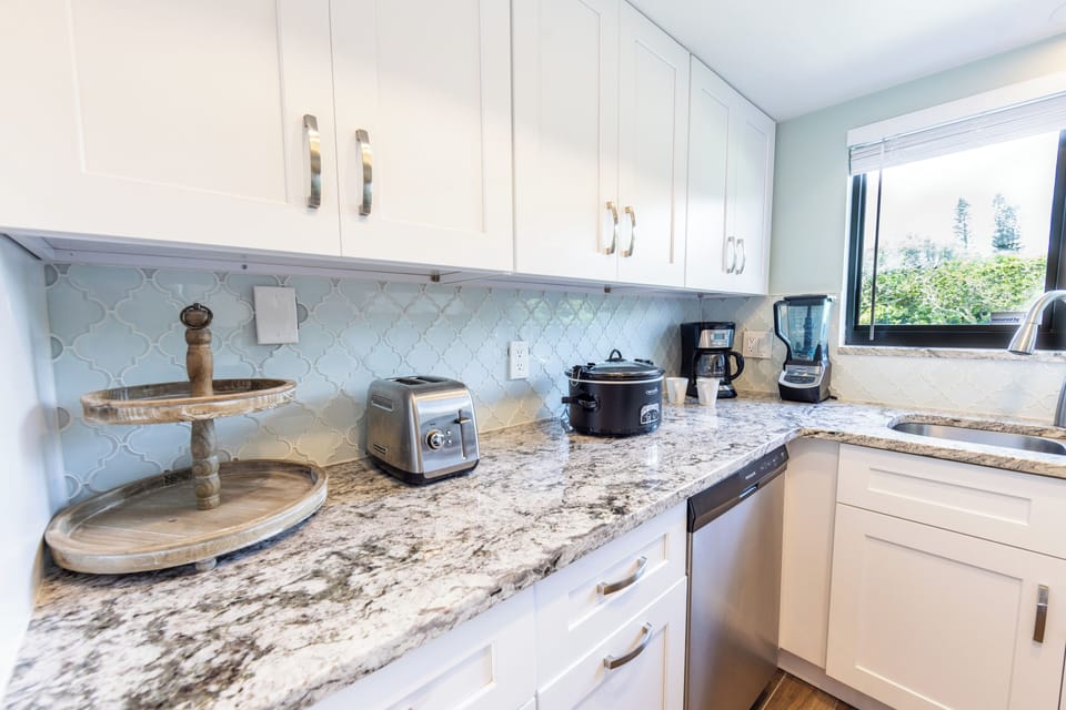 Modern kitchen with granite counters, coffee maker, and full appliances
