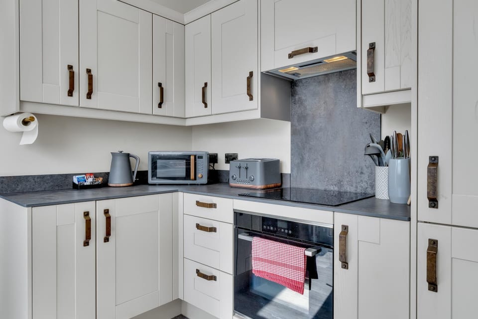Contemporary kitchen with induction hob, oven, microwave, fridge-freezer, and breakfast bar seating