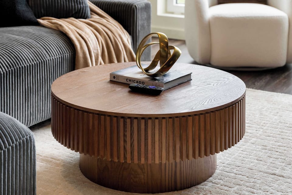 Elegant living room corner w/ sculptural coffee table & refined, neutral finishes.