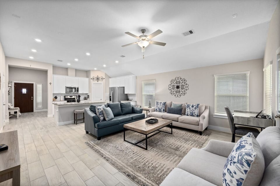 Spacious living room with comfy seating, stylish decor, and open flow to the kitchen and dining area.