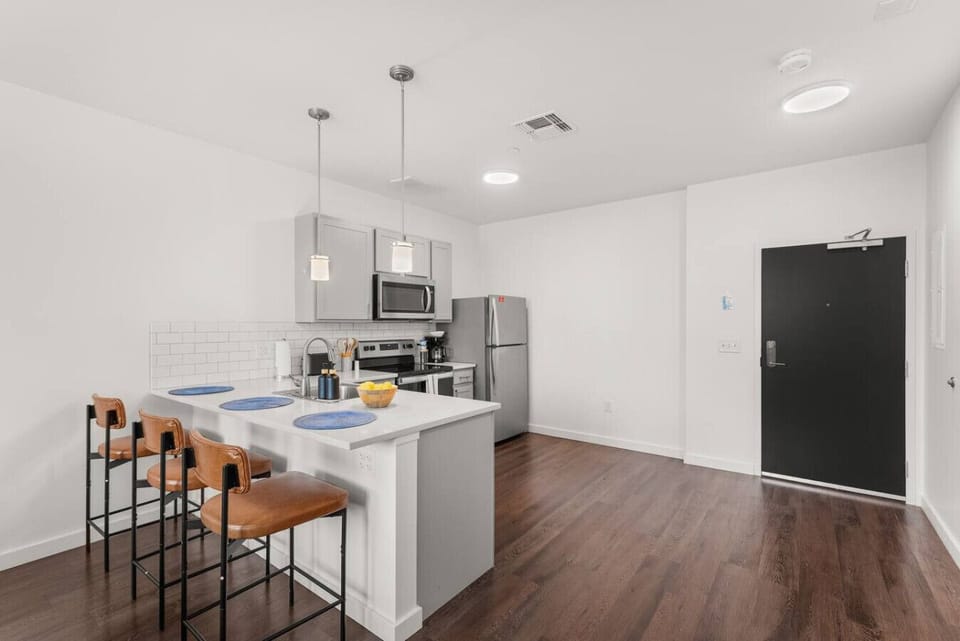 Modern kitchen with quartz countertops, stainless steel appliances, and island seating.