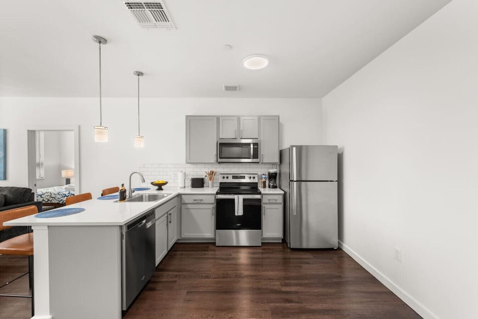 Fully equipped kitchen with quartz countertops, stainless steel appliances, and breakfast bar
