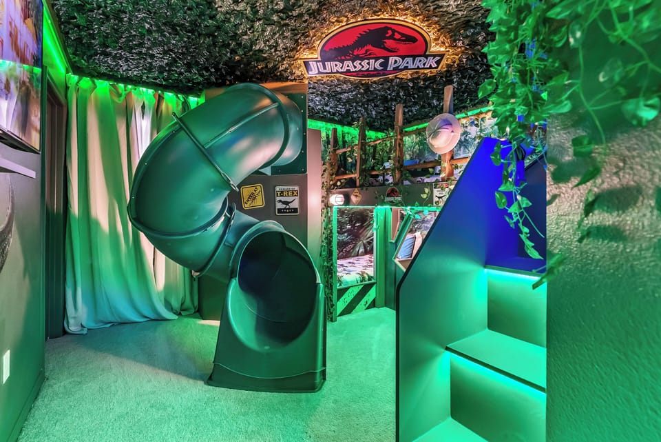 Discover a lively Jurassic Park-themed playroom with a twisting slide and vibrant green accents that spark adventure. The soft flooring and playful decor create an energetic space that's perfect for kids to explore and enjoy.