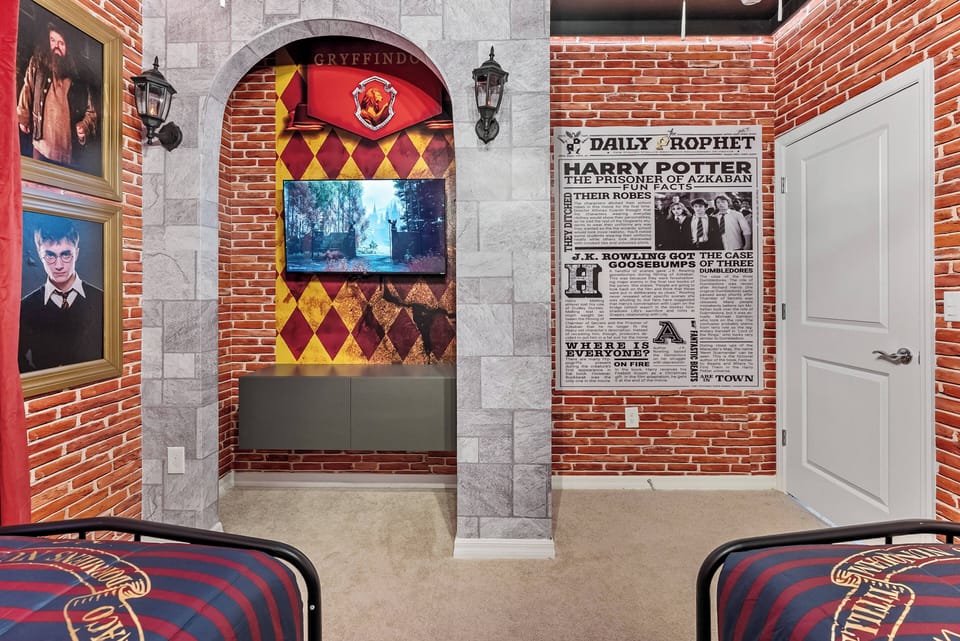Step into a whimsical world with this creatively themed bedroom, featuring exposed brick walls and vibrant house banners. Cozy twin beds invite relaxation, while a clever media area showcases beloved moments from an iconic series.