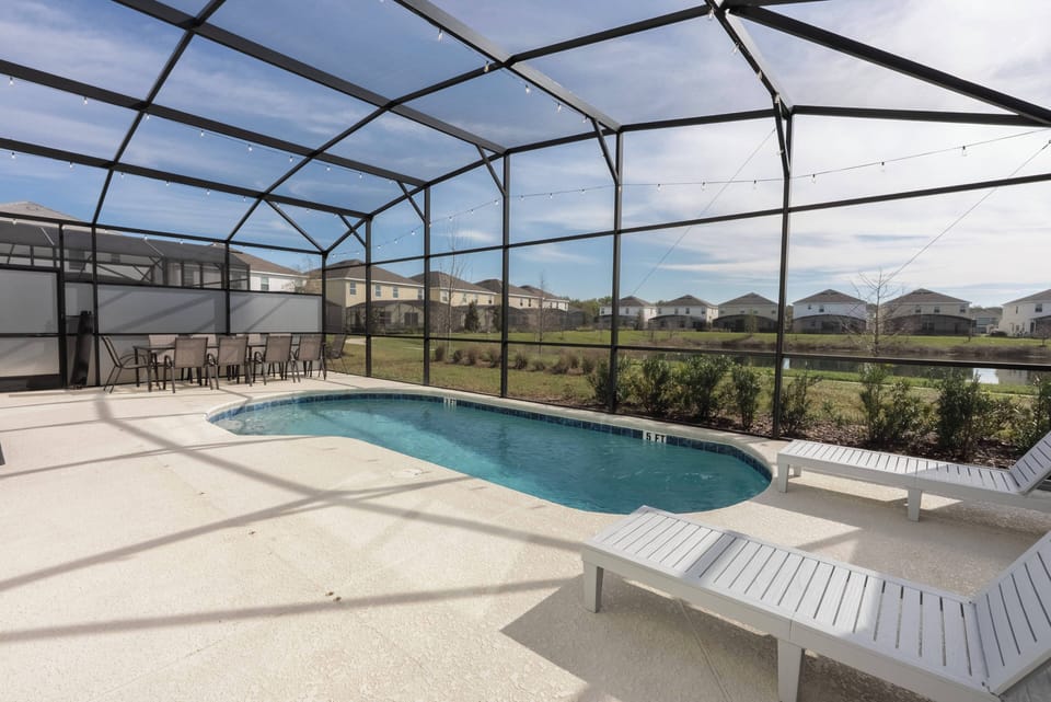 Step outside to your private oasis with a sleek pool and roomy white lounge chairs ideal for sunbathing. The screened enclosure connects you to the lush greenery, making your relaxation experience even more enjoyable.