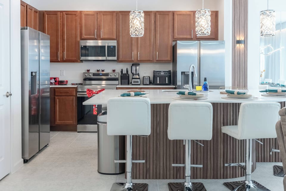 Explore this beautiful kitchen featuring stainless steel appliances and rich wooden cabinetry. The spacious island with stylish bar stools is ideal for casual dining and lively conversations in inviting natural light.
