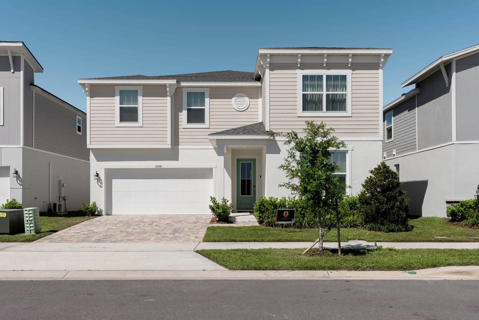 This charming home features a warm exterior with soft beige siding and a welcoming blue front door. The neatly landscaped yard showcases fresh greenery, creating an inviting approach that sets the tone for a delightful stay.