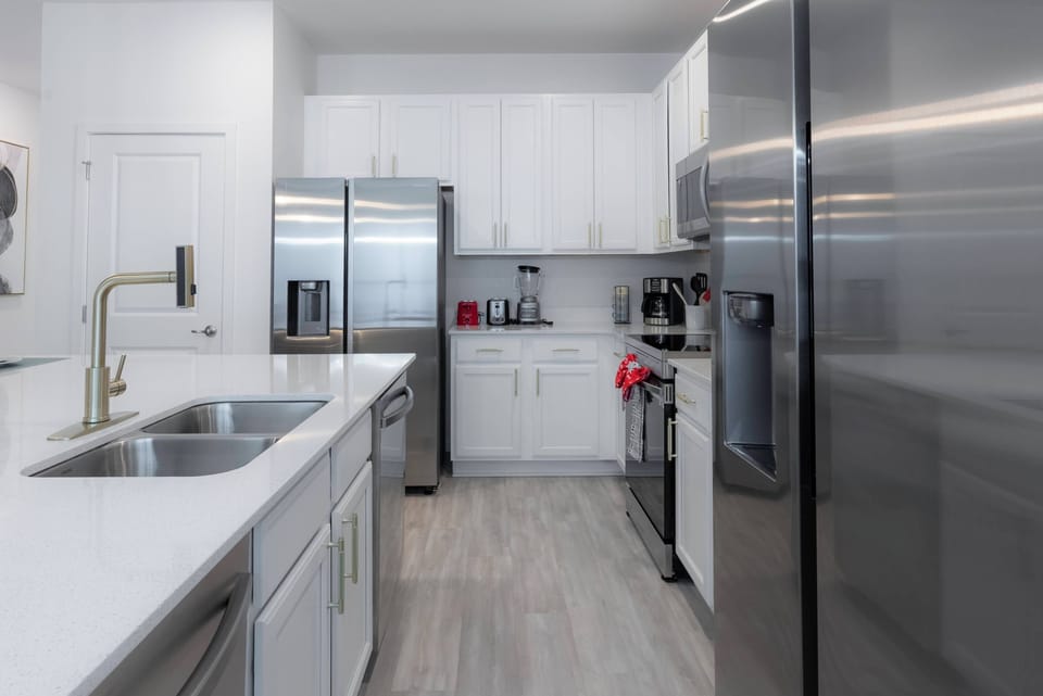 Discover a chic kitchen with stainless steel appliances and bright white cabinetry that offers a fresh feel. Ample countertop space and modern fixtures make meal prep and casual dining a breeze for your comfort.