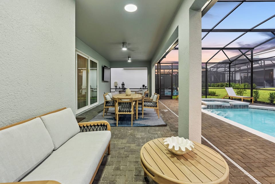 Discover the charm of our outdoor lounge with a stylish light gray sofa and natural wood accents that invite relaxation. Enjoy fresh air in the screened enclosure, just steps from the shimmering pool awaiting your enjoyment.