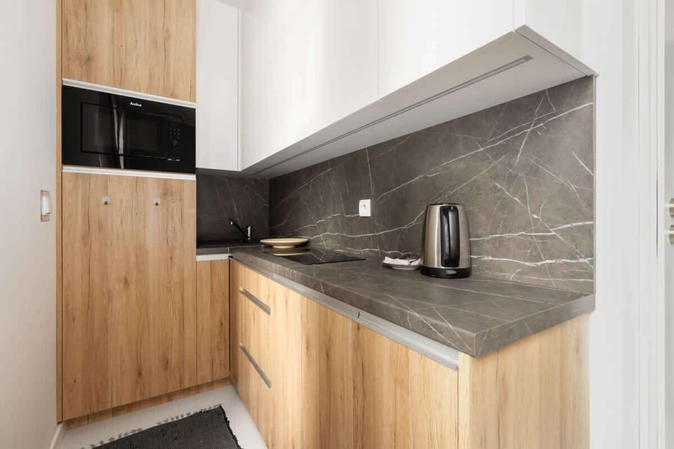 Compact kitchenette with modern wooden cabinetry, a kettle, and a convenient workspace for meal preparation.

