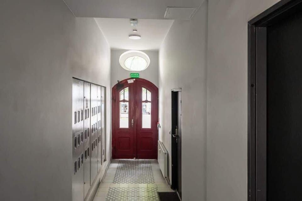 Elegant common area with a view of the building's interior staircase and red arched doors.

