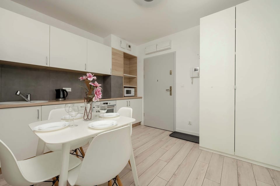 Bright and cosy living room with a capacious wardrobe, white kitchenette, dining area for four people and television.