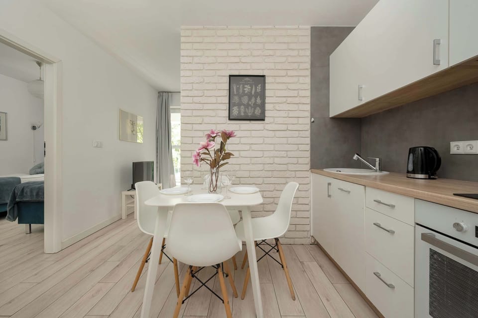 Modern white dining table with four chairs situated next to the kitchenette.