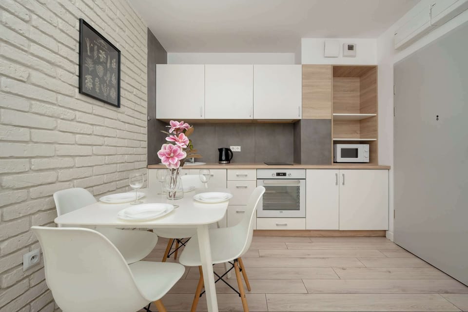 Functional white kitchenette with a microwave, an oven, a fridge, a freezer and an electric kettle.