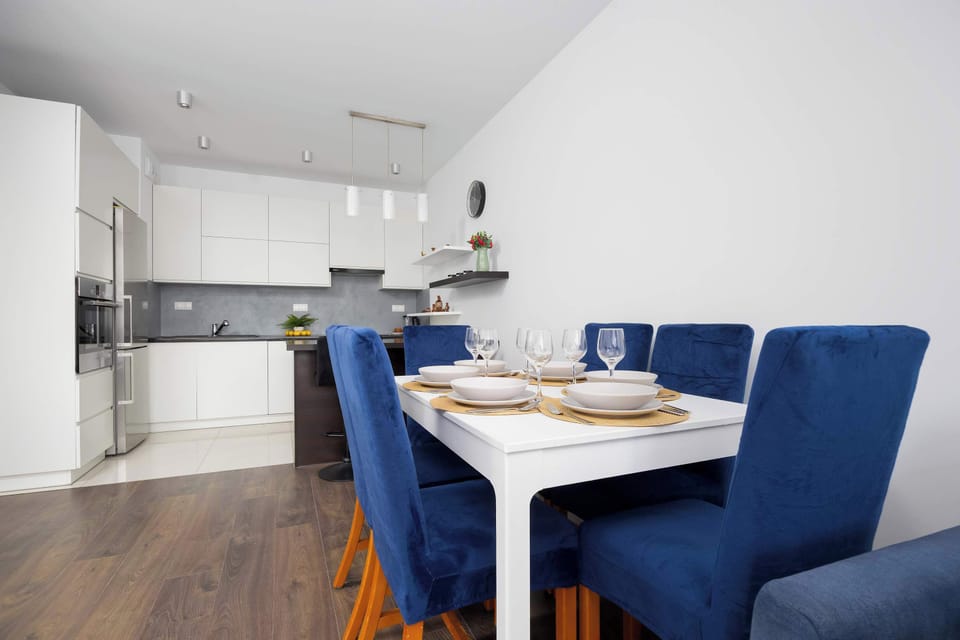 Bright white kitchenette with contemporary furnishings and blue chairs.