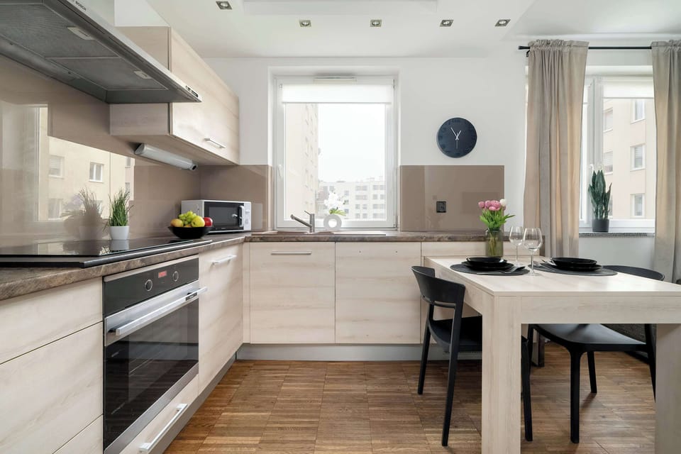 A modern kitchenette with sleek white cabinetry, built-in appliances, and a spacious countertop, perfect for preparing meals. The open layout seamlessly connects it to the living area.