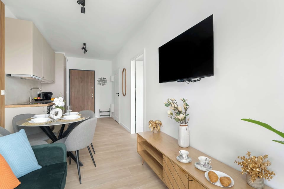 A bright living room with a comfortable sofa, TV, and wooden accent wall, seamlessly connected to the dining area.