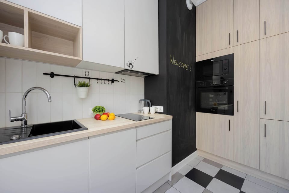 Welcome to this modern and functional kitchenette, featuring sleek countertops, ample cabinet space, and a welcoming chalkboard wall, perfect for preparing your favorite meals.