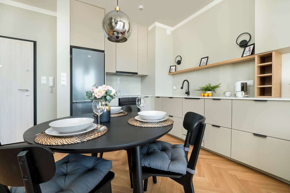 Black dining table with chairs located next to the functionally equipped kitchenette, where the guests can conveniently prepare meals.