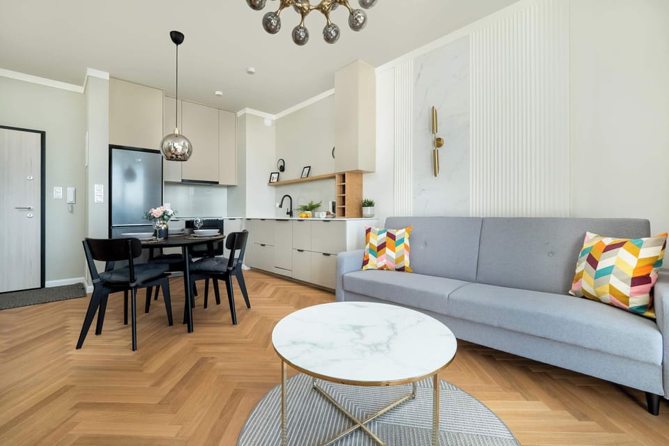 Light grey single sofa bed located next to the elegant dining area and white kitchenette.