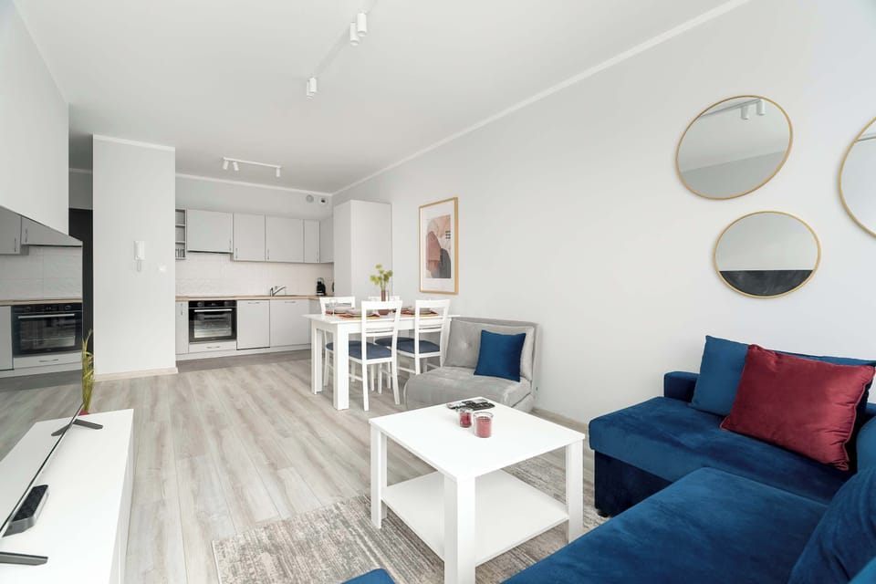 Living room with an exit to the balcony, coffee table, double sofa bed, television, and dining table.