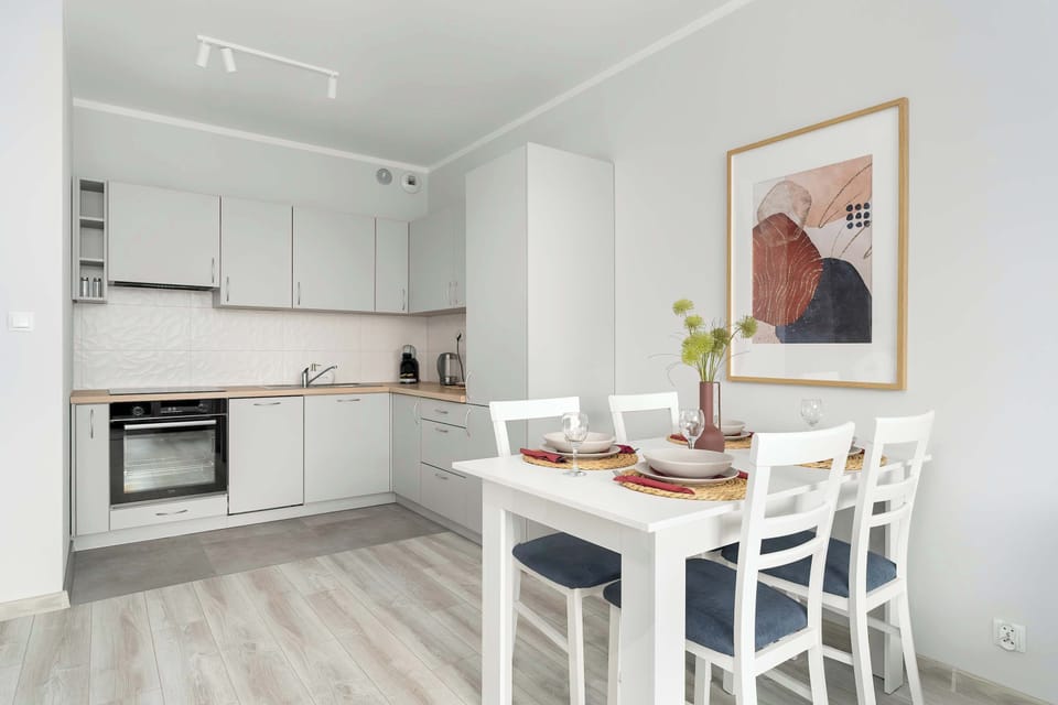 Functional dining area located next to practically equipped kitchenette with such appliances as an oven, a kettle, and a dishwasher.