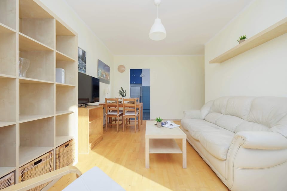 Bright living room with a sofa bed, TV, dining area and exit to balcony.