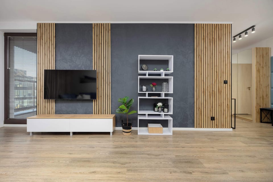 A view of the living room highlighting the entertainment area with a flat-screen TV, wooden shelving, and decorative accents.