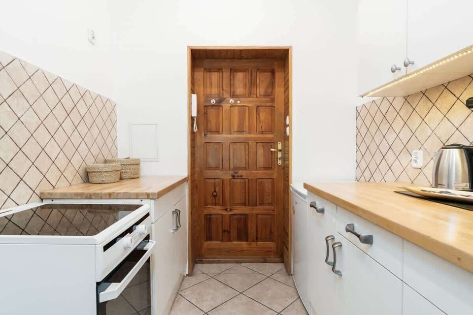 A cozy kitchen with a wooden door, tiled backsplash, and modern appliances, perfect for preparing meals.







