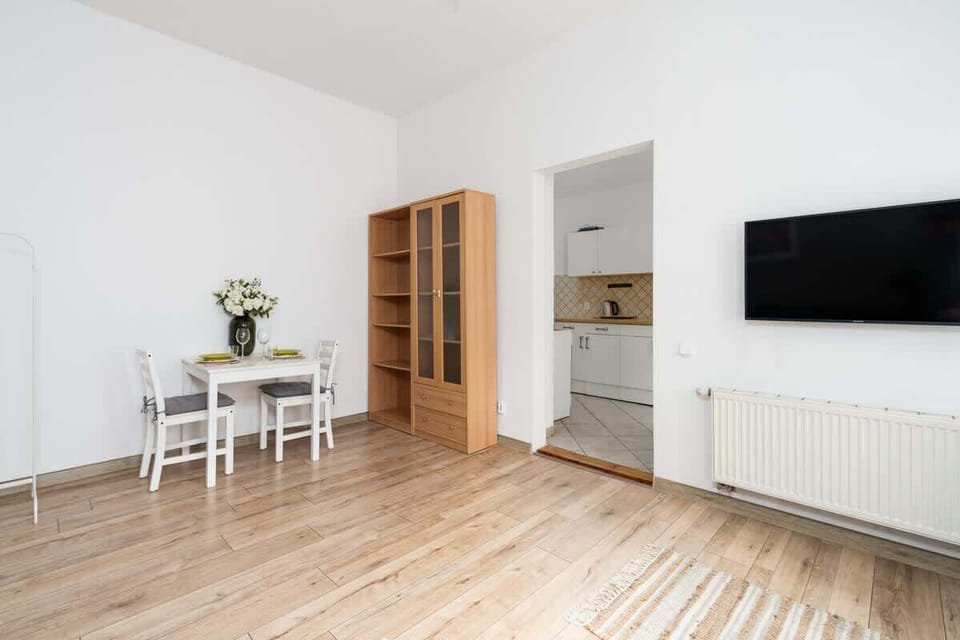 A wide view of the living area, featuring light-colored furniture, a bookshelf, and minimalist decor.

