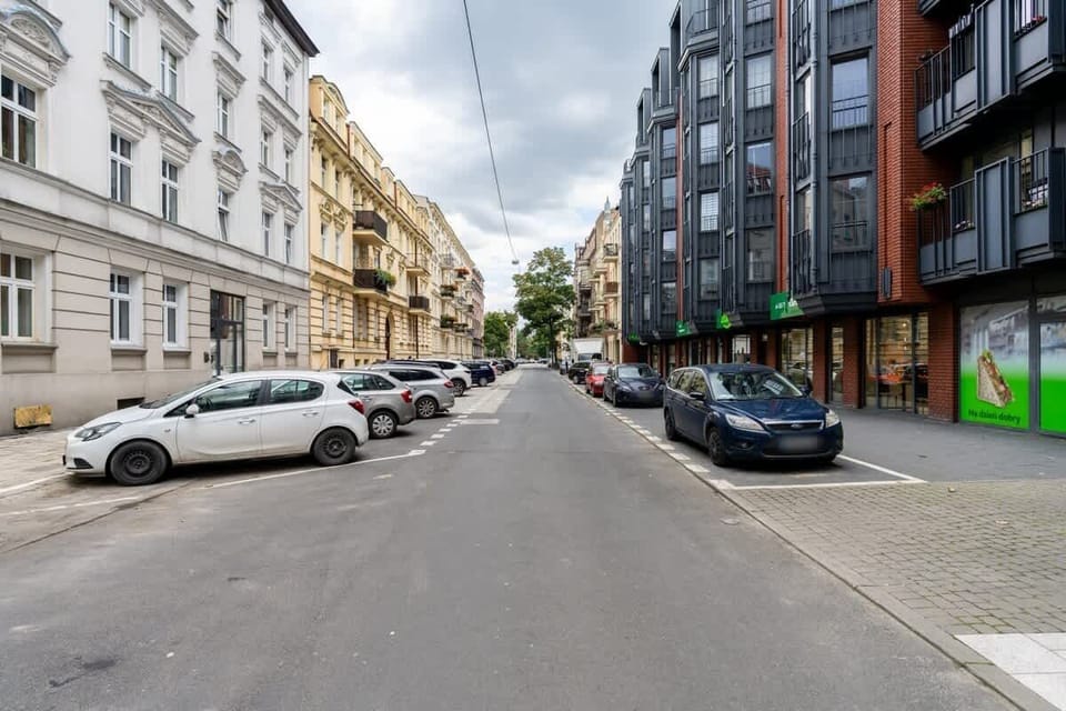 A quiet neighborhood street with parked cars and a mix of modern and traditional buildings, offering a comfortable urban setting.







