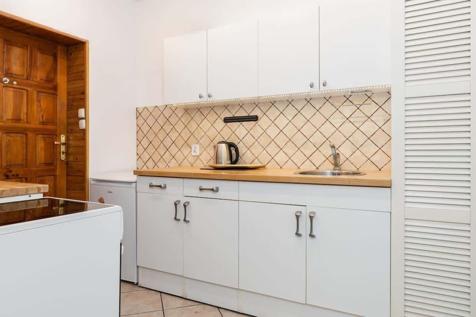 A modern kitchen with white cabinets, wooden countertops, and a tiled backsplash for a functional yet stylish look.

