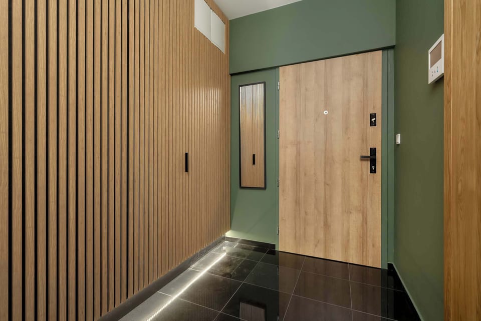 The hallway is sleek and modern, with wood paneling and a mirror that adds depth and functionality. It connects seamlessly to the rest of the apartment.