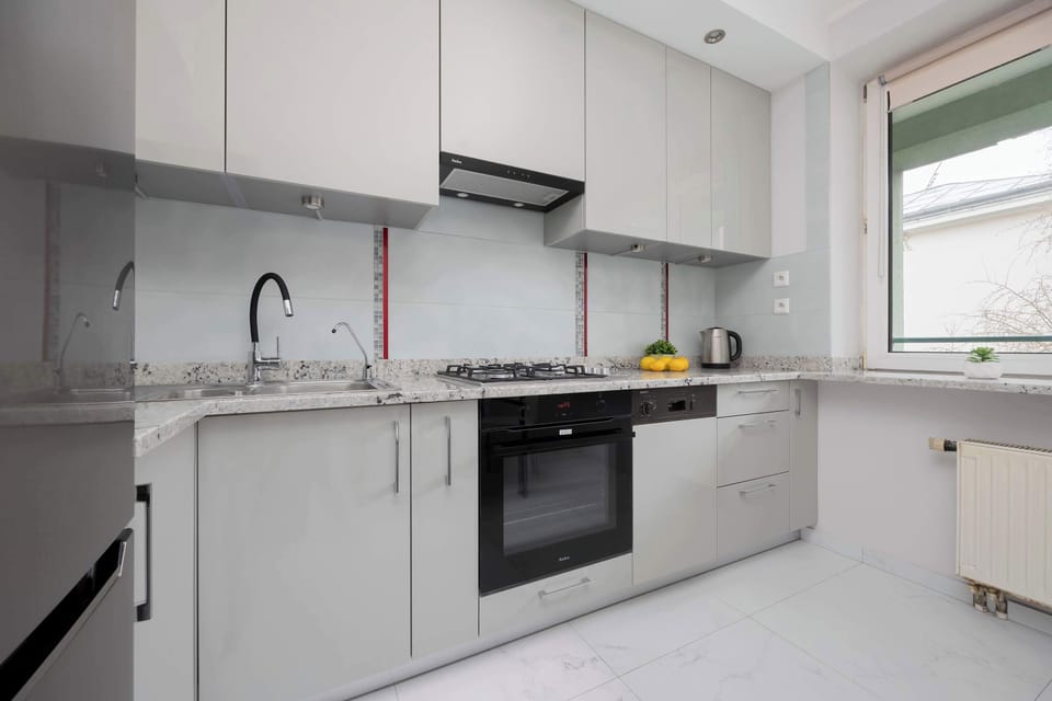 A sleek, modern kitchen with white cabinets, a marble countertop, and built-in appliances.