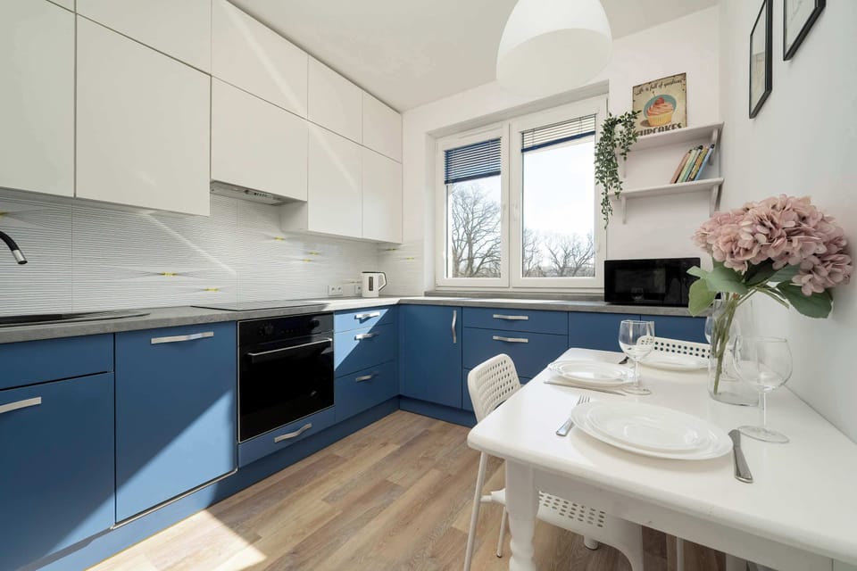 A modern kitchen with white and blue cabinets, a grey worktop and light-coloured flooring create a striking contrast.