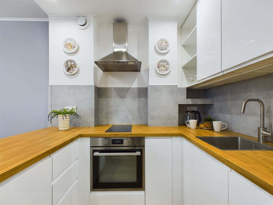 Fully equipped kitchen with sleek white cabinets and wooden countertops.