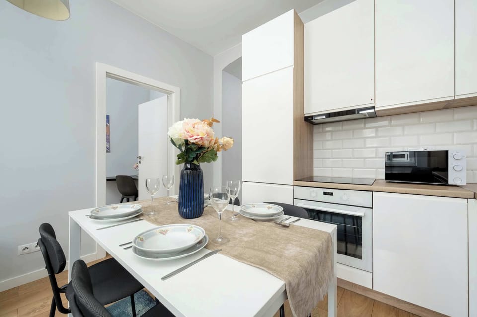 A full view of the white kitchenette, featuring a stove, oven, and minimalist cabinets.
