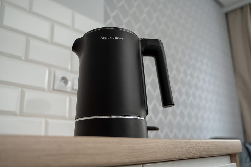 A black electric kettle placed on the counter of the kitchenette, highlighting small appliances.