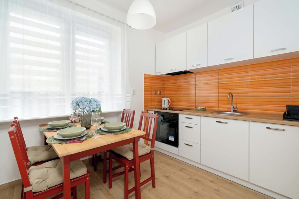 Fully equipped kitchen with electric cooktop, oven, dishwasher, refrigerator with freezer, electric kettle and dining area.