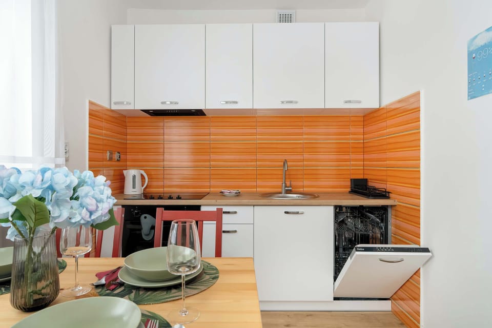 Fully equipped kitchen with electric cooktop, oven, dishwasher, refrigerator with freezer, electric kettle and dining area.