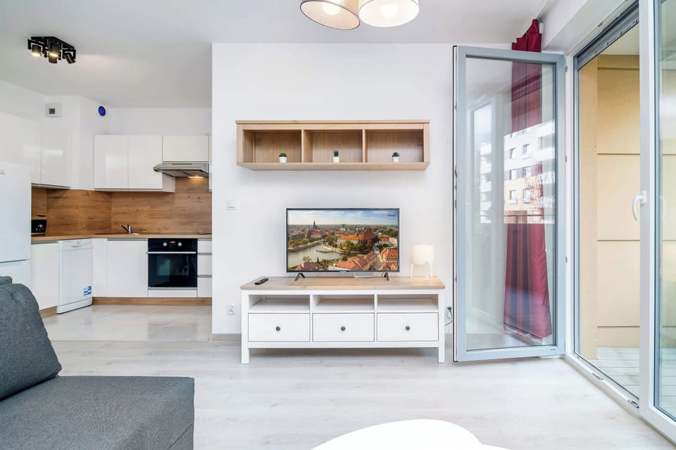 A bright living area featuring a comfortable sofa, large windows, and minimalistic design elements for a cozy feel.
