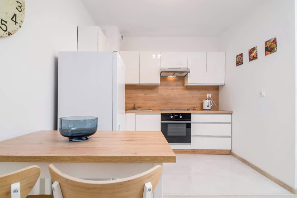 A kitchen with a combination of white cabinets and a wooden countertop, equipped with sink, and other essential appliances.