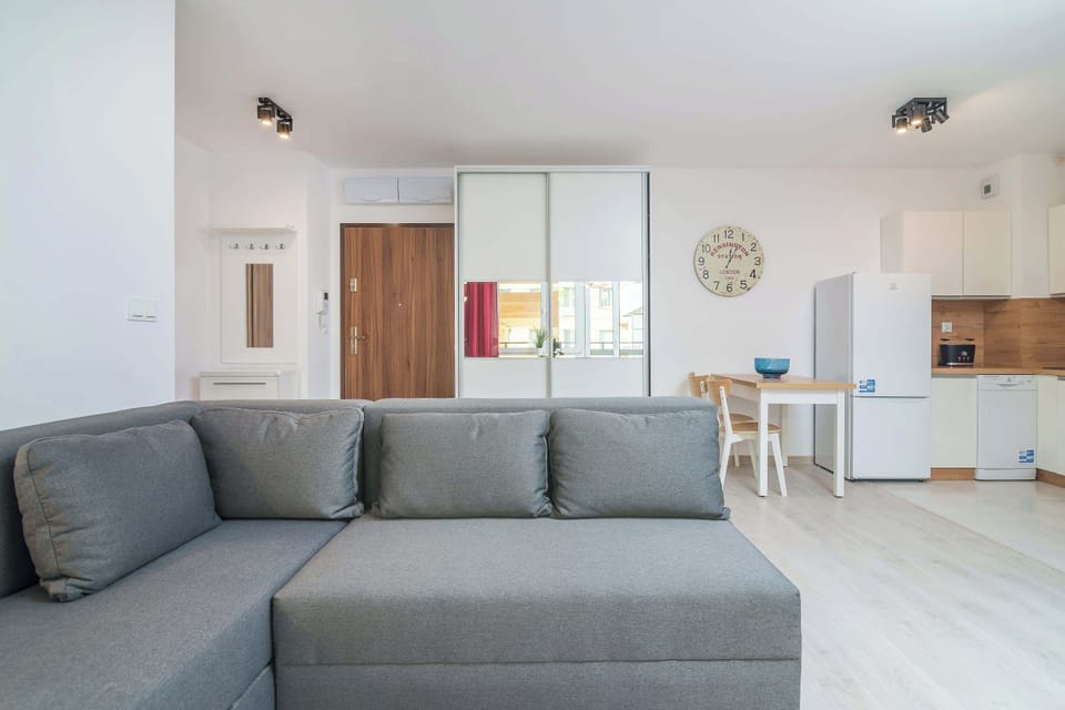 A cozy living room with a gray sofa as the main feature, accented by a white coffee table and large windows letting in plenty of light.