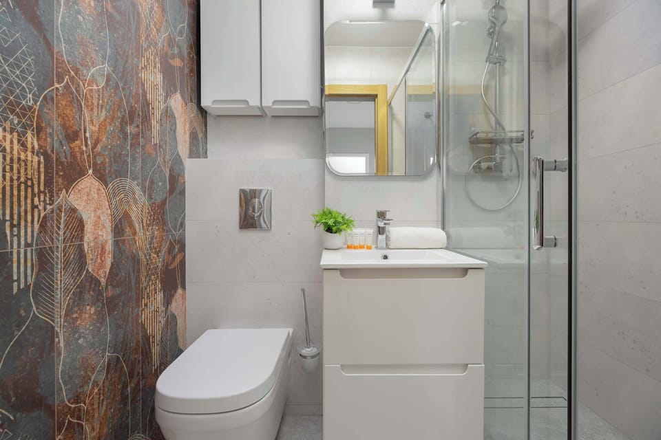A modern bathroom with a glass shower, white sink, and marble-style tiles.