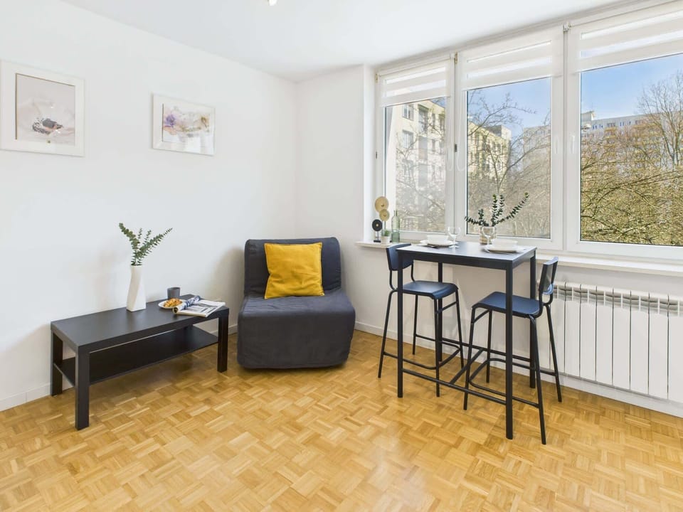 A small dining table with chairs next to the bed, providing a comfortable space for meals or work.