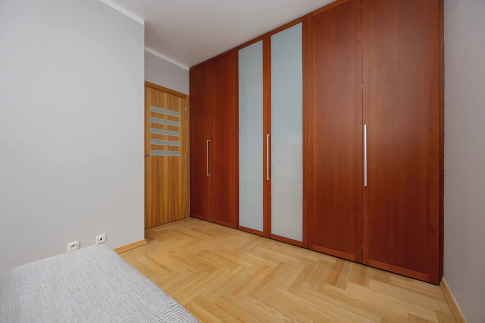 A bedroom with a navy blue bedspread and a minimalist wardrobe in the corner.