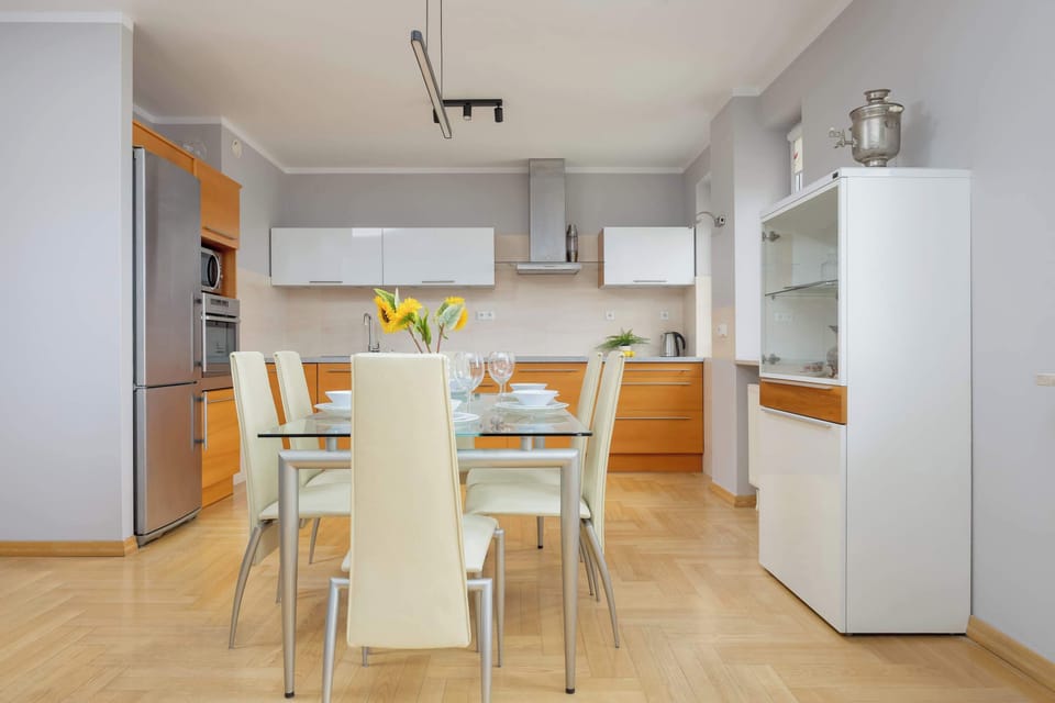 A close-up of a dining table with sunflowers and place settings, next to a built-in oven and microwave unit.