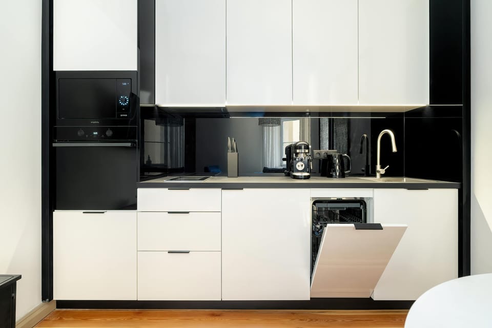 The modern kitchen with white furniture is equipped with high-quality appliances for preparing home-cooked meals.