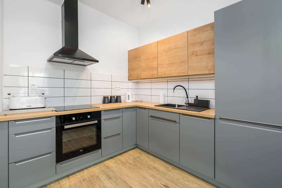 Kitchen with a minimalist design featuring wooden cabinetry, a black countertop, and gray accents, combining functionality and style.