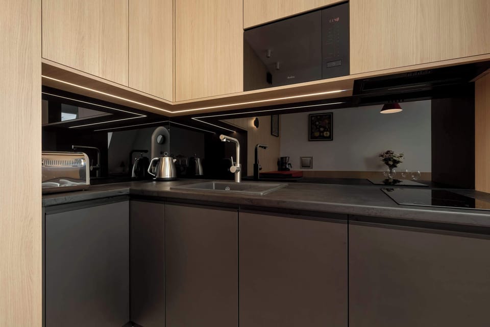 Another view of the compact kitchen, this time showing a kettle and built-in appliances, framed by modern cabinetry.